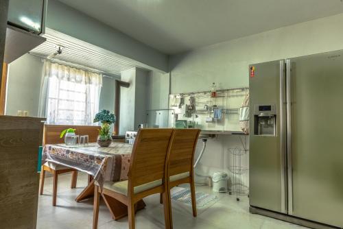 eine Küche mit einem Tisch und einem Kühlschrank in der Unterkunft Apartamento Completo de 2 quartos em Gramado in Gramado