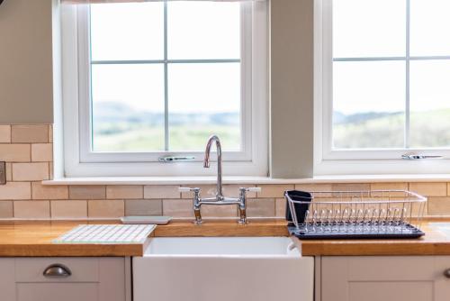 a kitchen with a sink and two windows at Hillcrest - 8 Person Luxury House Hot Tub in Hawick