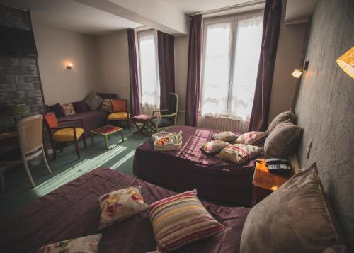 Una habitación de hotel con dos camas y una sala de estar. en Hôtel De La Banniere De France, en Laon