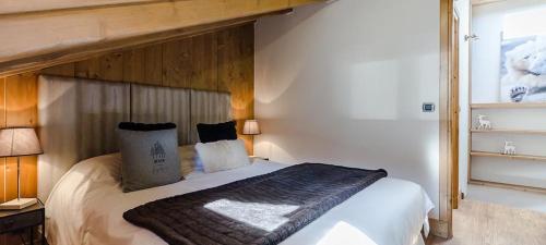 une chambre avec un grand lit avec une tête de lit en bois dans l'établissement Appart 6 pers 3 étoiles centre proximité remontées mécanique Courchevel Le Praz - Los Robles, à Courchevel