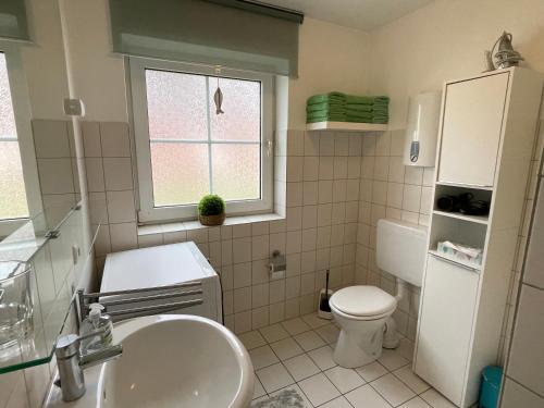 a bathroom with a sink and a toilet and a window at Meine Ferienwohnung in Fehmarn