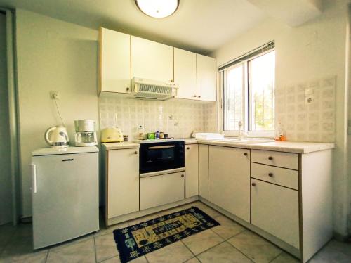 uma cozinha com electrodomésticos brancos e uma janela em Maris full apartment with roof garden access em Quios