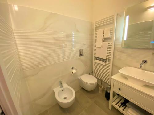 a white bathroom with a toilet and a sink at Nicolaus in Sesto Calende