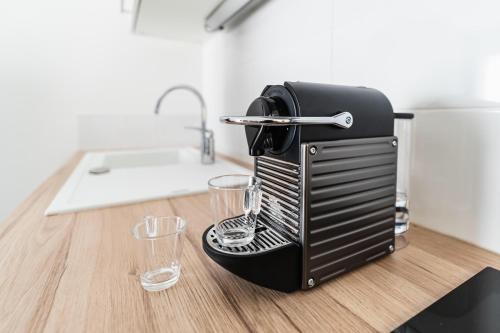 a coffee maker sitting on a table with two glasses at Cocoon Appart 1 Miribel in Miribel