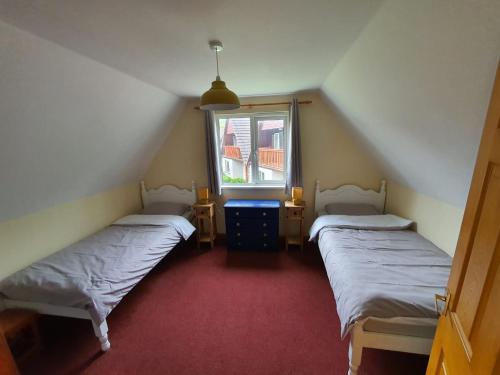 a attic room with two beds and a window at Blissful Escape Hengar Manor in Bodmin
