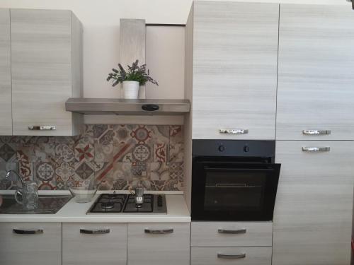 uma cozinha com armários brancos e um forno com placa de fogão em Maison Mafalda em Surbo