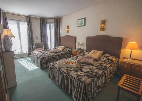 a hotel room with two beds and a couch at Hôtel De La Banniere De France in Laon