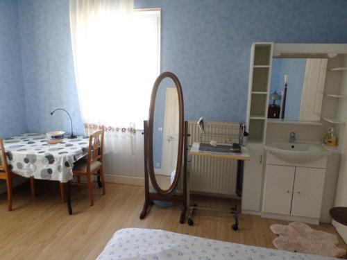 ein Badezimmer mit einem Tisch, einem Spiegel und einem Waschbecken in der Unterkunft Chambre individuelle à lit double dans une maison de Maître de 1904 in Haguenau