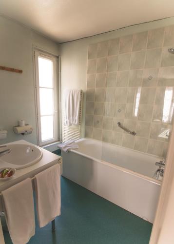une salle de bain blanche avec une baignoire et un lavabo dans l'établissement Hôtel De La Banniere De France, à Laon