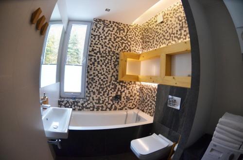uma casa de banho com um lavatório, uma banheira e um WC. em HARLEY FAMILY APARTAMENT em Muszyna