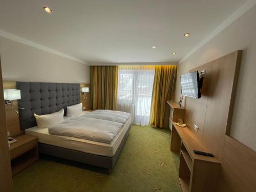ein Hotelzimmer mit einem Bett und einem TV in der Unterkunft Hotel Styrolerhof in Steeg