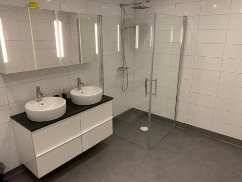 uma casa de banho com 2 lavatórios e uma cabina de duche em vidro. em Torups Vandrarhem em Torup