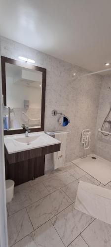 a bathroom with a sink and a mirror and a tub at Hotel Meurice in Calais