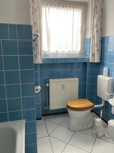 a blue tiled bathroom with a toilet and a window at Ferienwohnung Wegener in Neetze