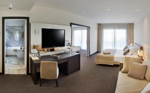 una grande camera d'albergo con letto e televisore di Cosmopolita Hotel Boutique & Spa a Platja  d'Aro
