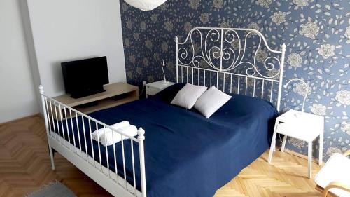 - une chambre avec un lit bleu et une télévision dans l'établissement Eozin Apartman, à Pécs