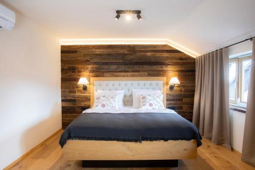 a bedroom with a wooden accent wall and a bed at House Troha - Rooms & Apartments in Bled
