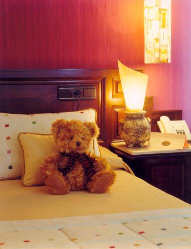 a teddy bear sitting on a bed with a lamp at La Rectoral in Taramundi