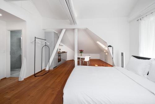 a bedroom with a large white bed and a wooden floor at The Studios Montreux - Swiss Hotel Apartments in Montreux