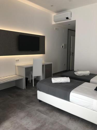 a bedroom with two beds and a desk and a tv at Sesto Senso Home in Santa Maria del Cedro