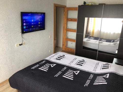 a bedroom with a bed with a tv on the wall at Happy Guest Apartament in Jūrmala