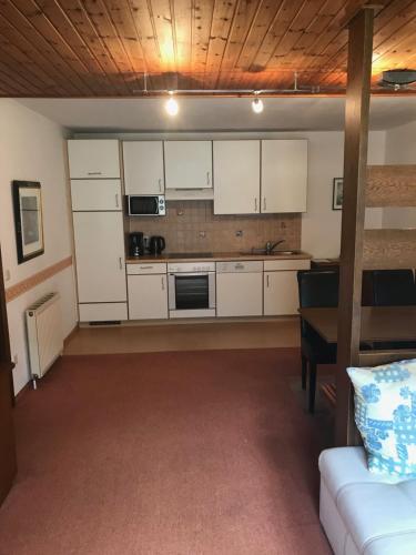 a kitchen with white cabinets and a couch in a room at Appartements Landhaus Jäger in Filzmoos