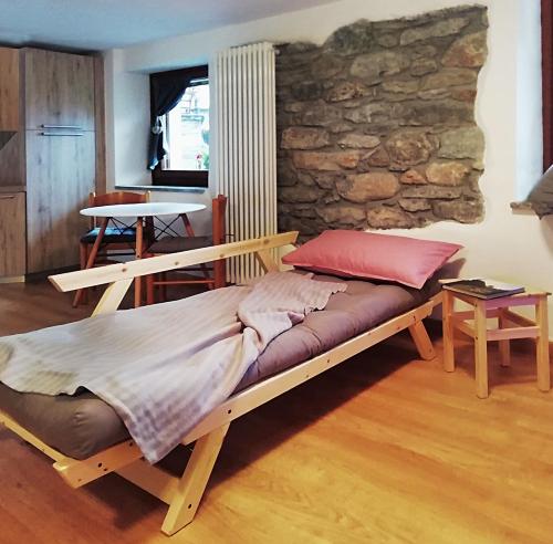 Cama de madera en habitación con pared de piedra en Casa Coccolin, en Emarese