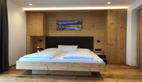 ein Schlafzimmer mit einem großen Bett und einer Holzwand in der Unterkunft B&B Obermair in Bruneck