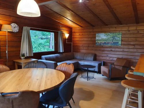 a room with a couch and a table and chairs at Vakantieoord De Bronzen Emmer in Meppen