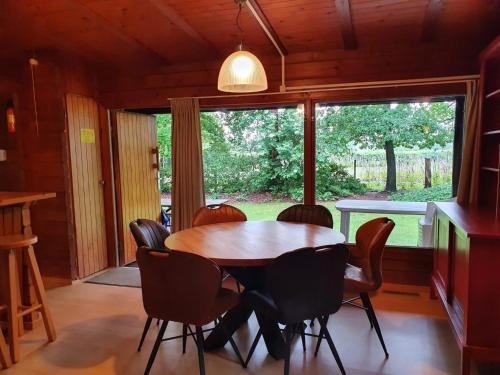 a dining room with a table and chairs and a window at Vakantieoord De Bronzen Emmer in Meppen