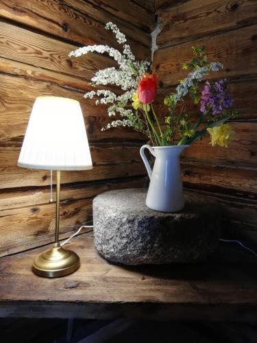 un vase de fleurs assis sur un rocher à côté d'une lampe dans l'établissement Brīvupes, à Balvi