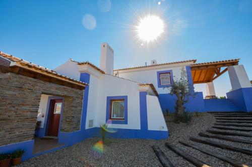 a blue and white house with the sun in the sky at Ares do Monte - Turismo Rural in Cercal