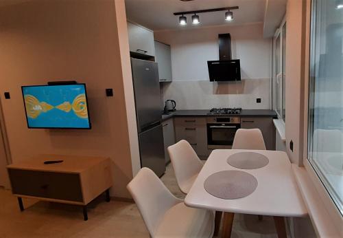 eine kleine Küche mit einem weißen Tisch und weißen Stühlen in der Unterkunft Cosy and Bright Apartment in Gizycko in Giżycko