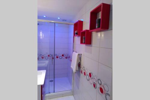 La salle de bains blanche est pourvue de placards rouges et d'une douche. dans l'établissement Nid douillet F2, clim, jardin, piscine, parking, plage 200 m Palavas, à Palavas-les-Flots