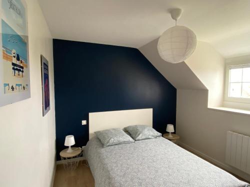 - une chambre avec un mur bleu et un lit dans l'établissement Appartement cosy et neuf au pied des commerces, à Pléneuf-Val-André