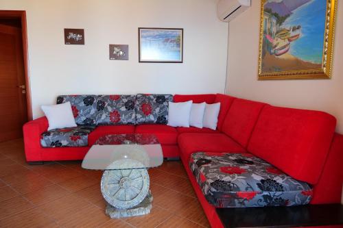 a living room with a red couch and a table at Villa Crystal in Sarandë