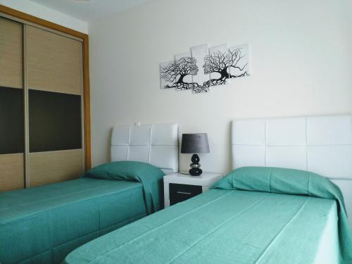two beds in a room with green sheets at Apartamento T2 Eucalipto 2A in Olhos de Água