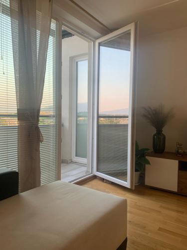 een slaapkamer met een bed en een groot raam bij Artemis Apartment - nice, family friendly and cozy in Skopje