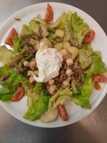 a white plate with a salad on a table at Auberge du Raddon in Raddon-et-Chapendu