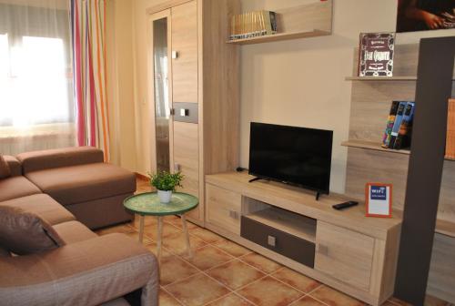 - un salon avec une télévision, un canapé et une table dans l'établissement Viviendas de uso turisitco Dulcinea, à Ventas con Peña Aguilera