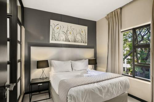 a bedroom with a large bed and a window at Easy Stay - The Vantage Rosebank in Johannesburg