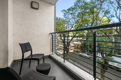 a balcony with a chair and a view of a car at Easy Stay - The Vantage Rosebank in Johannesburg