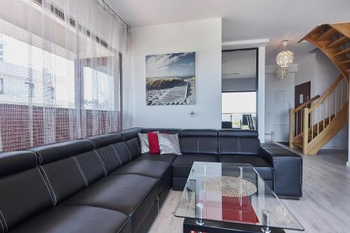uma sala de estar com um sofá preto e uma mesa de vidro em Apartamenty Świnoujście - Baltic Park em Świnoujście