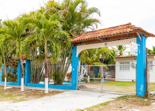 a blue gate in front of a house with palm trees at HOSPEDAJE VILLAMAR in Nueva Gorgona