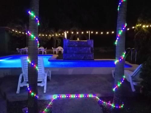 uma piscina com luzes de Natal em duas palmeiras em HOSPEDAJE VILLAMAR em Nueva Gorgona