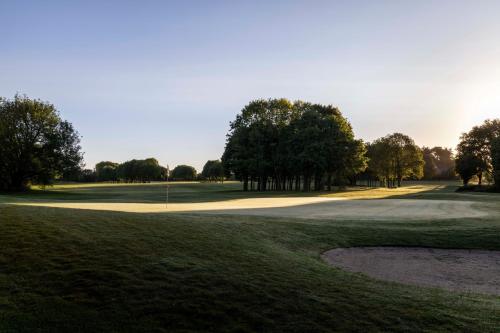 a view of a golf course with trees in the background at Hôtel Lancelot & Spa - Domaine du Roi Arthur in Ploërmel