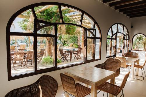 een kamer met een tafel, stoelen en ramen bij La Bohemia del Rio Hostal Boutique-Adults Only in Santa Eularia des Riu