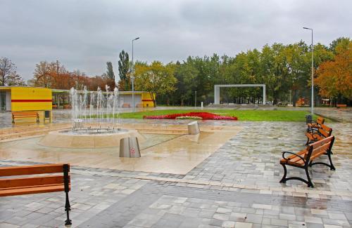 a park with two benches and a fountain at Napraforgó Vendégház in Mezőkövesd