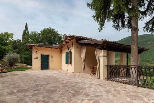 ein kleines Haus mit einer Terrasse und einem Baum in der Unterkunft Villa Gina Umbria Luxury Retreat in SantʼAnatolia di Narco
