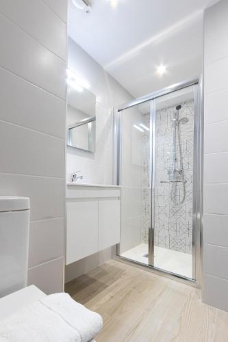 a white bathroom with a shower and a sink at The G Hotel by JL in St Julian's